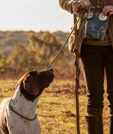 En kvinde med en hund i snor, der nyder en Essential Lamb Delights (lammelunger), en allergivenlig godbid lavet af 100% lamme snack.